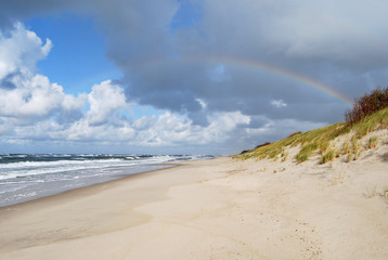 Rainbow over the white sandy beach and the Baltic Sea. Scenic seashore