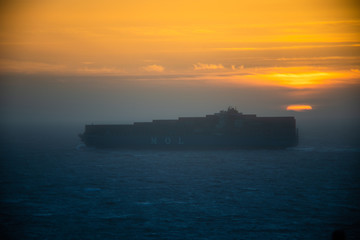 Fototapeta premium Misty tanker boat in fog against a colorful sunset