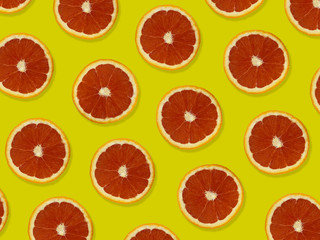 Creative pattern made of red oranges. top view of colorful fruit pattern of fresh red orange slices on yellow colorful background. 
