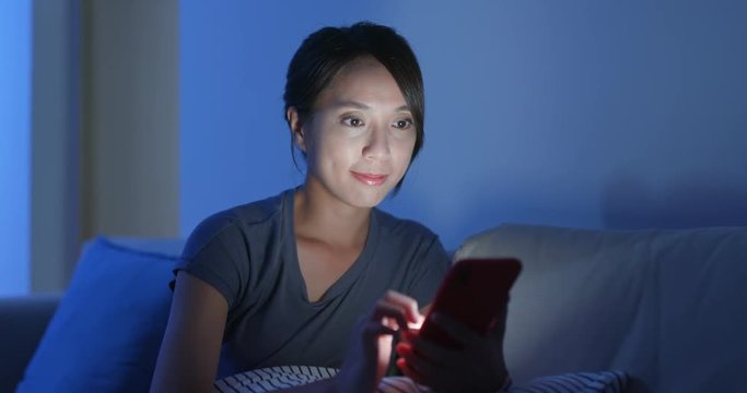 Asian woman reply sms on cellphone in the evening