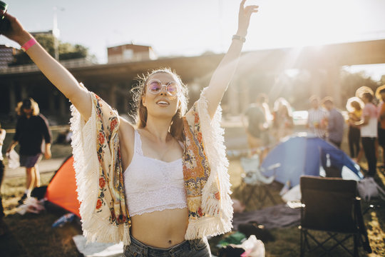 Happy young woman with arms raised enjoying at music event during summer
