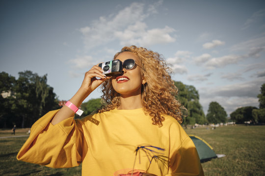 Smiling young woman photographing with camera on field against sky