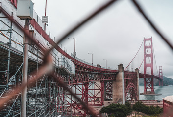 Golden Gate Bridge through a fence on a cloudy day