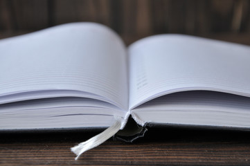 open notepad lying on a wooden table. The background is pinkish.