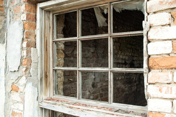 view of a window and a wooden window frame without glass in an abandoned old house