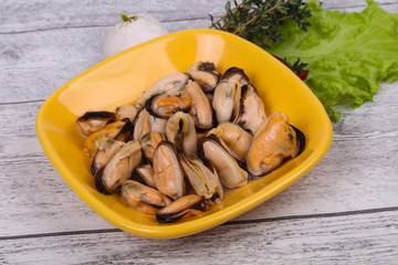 Pickled mussels in the bowl served pepper, garlic and salad