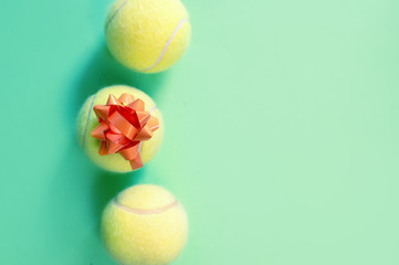 Three tennis balls with gift packaging on green background.