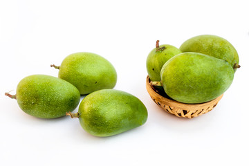 Raw organic kesar mangoes isolated on white in a basket along with some on surface.