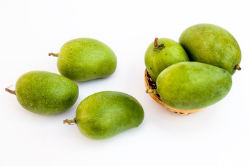 Raw organic kesar mangoes isolated on white in a basket along with some on surface.