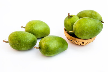 Raw organic kesar mangoes isolated on white in a basket along with some on surface.