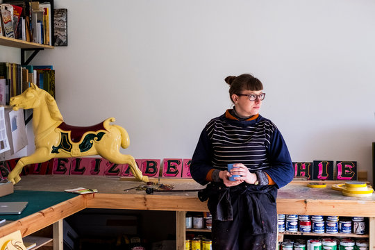 Woman in workshop with a traditional wooden carousel horse from merry-go-round.,Signwriter