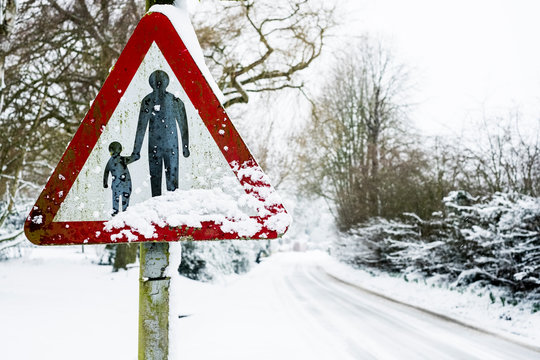 Close up of a 'Pedestrians in road' sign on side of snow-covered rural road.,Aston Rowant
