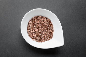White bowl with caraway on blackbackground. Top view, flat lay. Copy space. Natural light. Horizontal image. 