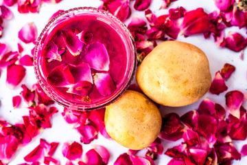Best face mask or face pack to reduce blemishes and dark patches isolated on white i.e. Rose petals well mixed with potato juice in a bowl and raw potato and rose petals present on the surface.