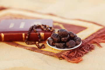 The book of the Islamic koran, dates and rosaries are beautifully laid out on the prayer mat in the desert. Ramadan Kareem