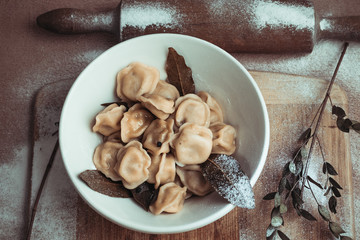 ready dumplings in a plate on a wooden board with flour and rolling pin decoration
