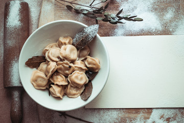 ready dumplings in a plate on a wooden board with flour and rolling pin decoration with Blank sheet