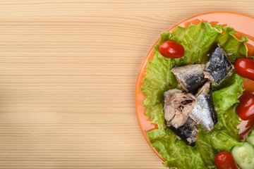 Pieces of sardine iwashi on lettuce leaves with red tomatoes and sliced cucumbers.
