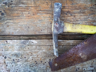 Rusty hand saw and hammer on old wooden boards.