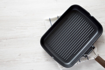 Overhead view, empty grill pan on a white wooden surface. Top view, from above, flat lay. Copy space.
