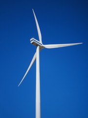 Wind power generator on an empty field. Green energy on a sunny day. Blue sky with clouds. Ecology and energy conservation concept.