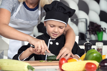 A family of cooks.Healthy eating.Mother and children prepares vegetable salad in kitchen.	