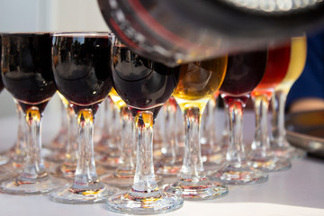rows of glasses of wine and someone serving different port wines