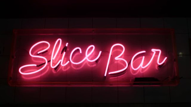 Bright fluorescent pink neon 'Slice Bar' pizza sign. The neon sign illuminates its surroundings making this a key feature to the growing establishment.