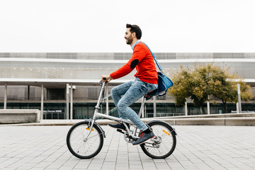 Casual businessman commuting in the city, using his folding bike