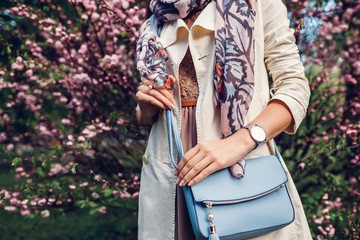 Young woman holding stylish handbag and wearing trendy outfit. Spring female clothes and...