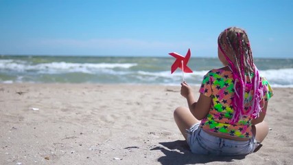 A girl holds a toy windmill in her hands
