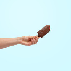 Female hand holding popsicles on a blue background.