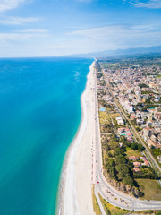Panoramica aerea del lungomare di Locri, in Calabria. La spiaggia bianca, il mare Mediterraneo blu e le case della città.
