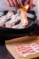young woman in a gray apron fries bacon