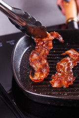 young woman in a gray apron fries bacon