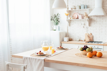 served table with pancakes, fruits and orange juice in kitchen - Powered by Adobe