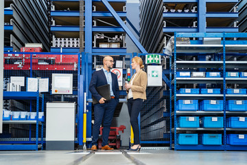 Businessman and businesswoman talking in factory