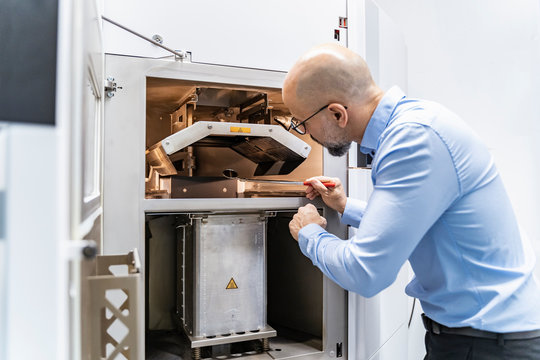 Man holding mirror examining d printer