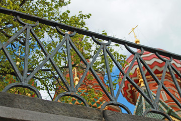 Multicolored domes of St. Basil's Cathedral in Moscow Russia through the lattice of the black fence