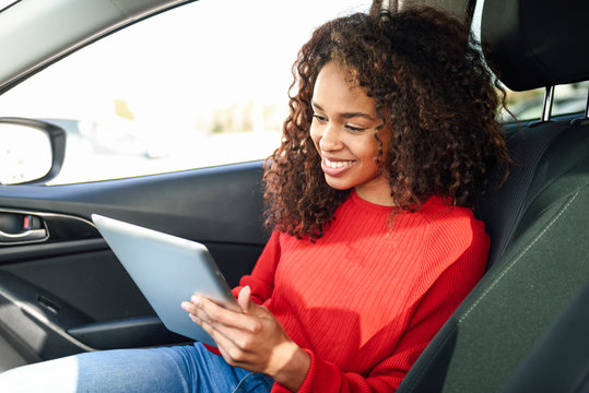 Smiling young woman using tablet in a car