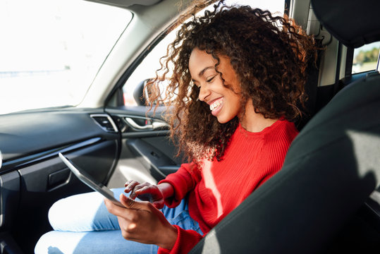 Happy young woman using tablet in a car