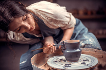 Stylish pottery woman enjoying pottery art and production process. The concept of craft creativity. - obrazy, fototapety, plakaty
