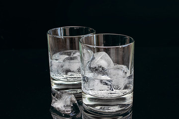 Two glasses of cold fresh tonic water with ice isolated on black background.