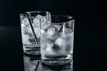 Two glasses of cold fresh tonic water with ice isolated on black background.