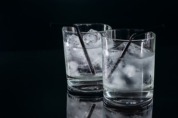 Two glasses of cold fresh tonic water with ice isolated on black background.