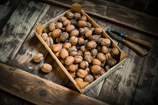 Walnuts in wooden box and nutcracker, wooden background