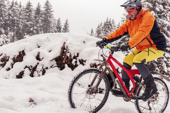 Man riding mountain bike on path in winter forest