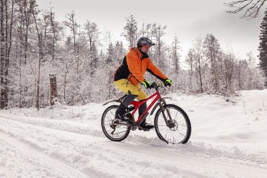 Man riding mountain bike on path in winter forest