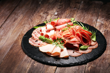 Food tray with delicious salami, pieces of sliced ham, sausages,salad and vegetable. Meat platter with selection