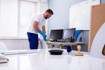 Janitor cleaning white desk in office